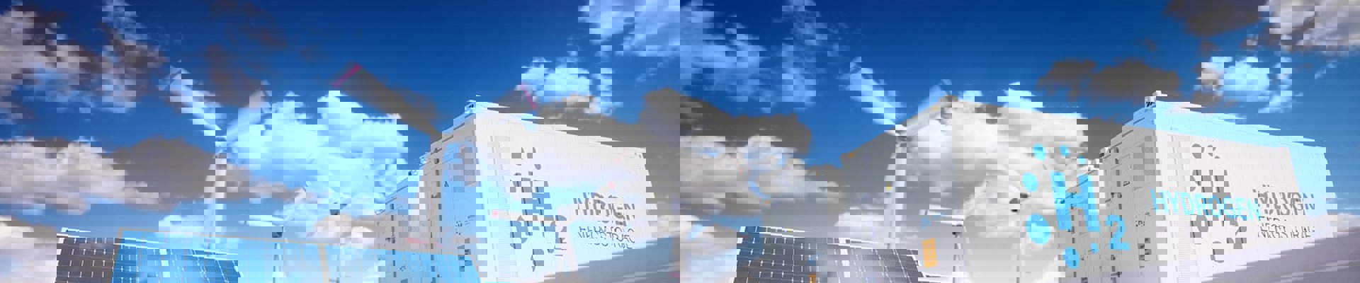 solceller, vindmølle og Hydrogen H2 foran blå himmel med skyer