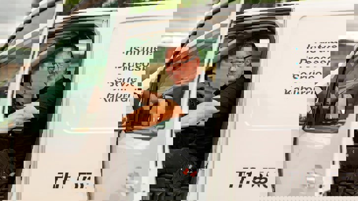 Servicemand fra insatech sidder smilende i bil med døren åben