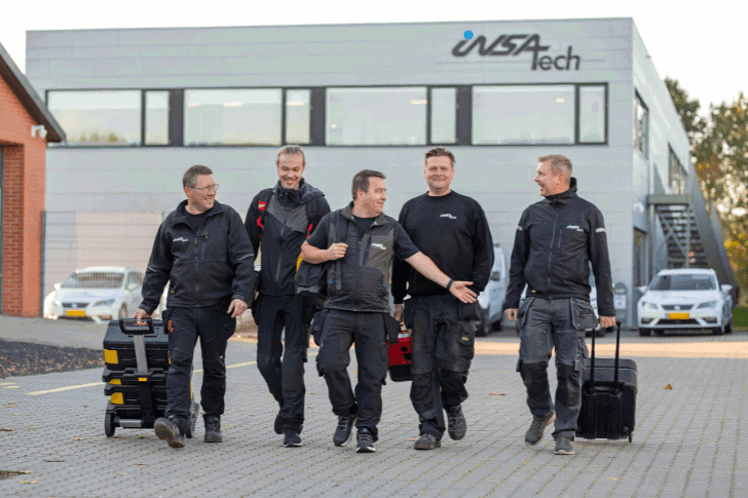Insatech Service team walking and smiling in front of the Insatech building.