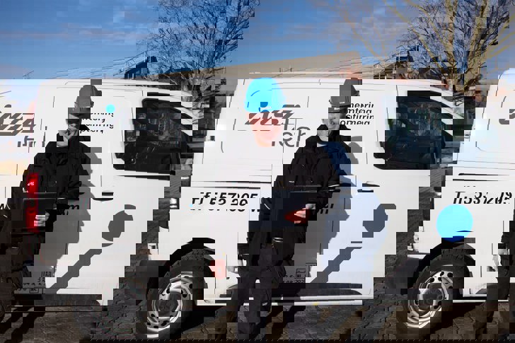 Insatech servicetekniker står foran bil med blå hjelm på