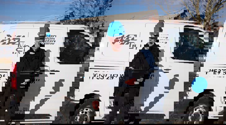 Insatech servicetekniker står foran bil med blå hjelm på